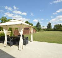Eine Terrasse mit Pavillon im Garten eines Einfamilienhauses in Rajka, umgeben von Grün und Rasen.