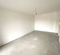 Ein leerer Raum in einer Zweizimmerwohnung mit weißen Wänden und Betonboden.