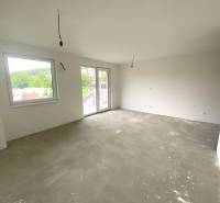 Geräumiges Zimmer einer 2-Zimmer-Wohnung mit großen Fenstern und Betonboden.