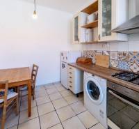 Die Küche in einer 2-Zimmer-Wohnung mit einem rustikalen Holztisch und bunten Fliesen.