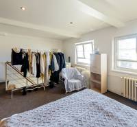 Helles Schlafzimmer in einer 2-Zimmer-Wohnung mit Schrank, Stuhl und Fenstern.