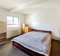 Schlafzimmer mit einem Holzbett, Schränken und hellen Wänden in einer 2-Zimmer-Wohnung.