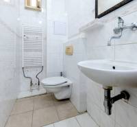 Badezimmer mit weißen Fliesen, Waschbecken, Toilette und Handtuchheizkörper in einer 2-Zimmer-Wohnung.