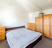 Schlafzimmer in einer Zweizimmerwohnung mit Holzmöbeln und Bibliothek.