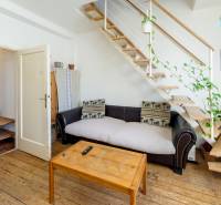Wohnzimmer in einer 2-Zimmer-Wohnung mit Treppe, Holzboden und Pflanzen.