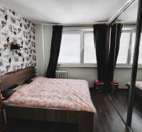 Schlafzimmer in einer 2-Zimmer-Wohnung mit großem Fenster, Schiebetüren mit Spiegeln und dekorativer Wand.
