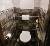 Badezimmer mit hängendem WC, Fliesen in einer 2-Zimmer-Wohnung mit dunklen Fliesen.