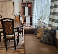 Esszimmer in einem Einfamilienhaus mit Holztisch, Stühlen und Sofa, helle Vorhänge.