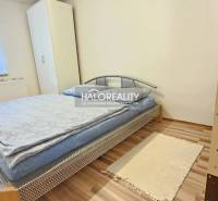 Ein Schlafzimmer in einem Einfamilienhaus, einfach eingerichtet mit einem Bett, einem Schrank und einem Holzboden.