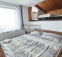 Ein Schlafzimmer in einem Einfamilienhaus mit einem einfachen Bett und einem Dachbodenbereich mit einem weiteren Bett.