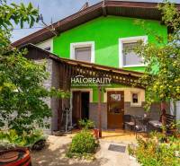 Ein Einfamilienhaus in Banská Štiavnica mit einer Holzveranda, umgeben von Grün und Obstbäumen.