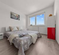 Ein Schlafzimmer in einer 4-Zimmer-Wohnung mit einem bequemen Bett, weißen Möbeln und modernem Dekor.