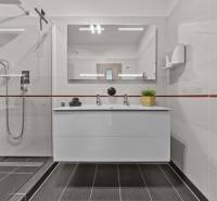 Badezimmer mit Waschbecken, Duschkabine und Spiegel in einer 4-Zimmer-Wohnung.