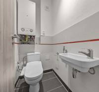 Badezimmer in einer 4-Zimmer-Wohnung mit Toilette, Waschbecken und einem Boiler an der Wand.