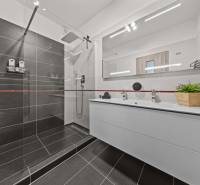 Badezimmer in einer 4-Zimmer-Wohnung mit Duschkabine und Doppelwaschbecken.