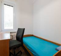 Einfaches Zimmer in einer 4-Zimmer-Wohnung mit Bett, Tisch und schwarzem Sessel.