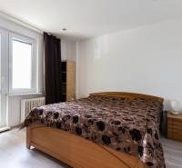 Schlafzimmer mit einem Holzbett und dunklen Vorhängen in einer 4-Zimmer-Wohnung.