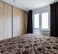 Schlafzimmer mit Einbauschrank, gepolstertem Überwurf und Fenster in einer Vierzimmerwohnung.