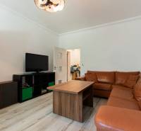Wohnzimmer in einer 4-Zimmer-Wohnung mit Ledersofa und Fernseher auf einem Schrank.
