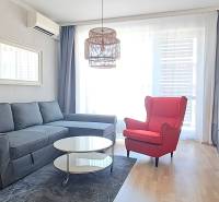 Wohnzimmer mit einem bequemen Sofa, einem roten Sessel und einem Fernseher in einer 2-Zimmer-Wohnung.