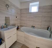 Badezimmer in einem Einfamilienhaus mit Badewanne und Waschbecken in hellen Farbtönen.
