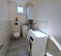 Waschküche in einem Einfamilienhaus mit Waschmaschine, Boiler und Toilette.