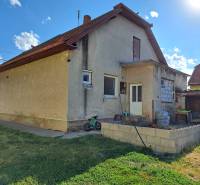 Ein Einfamilienhaus in Kmeťovo mit Terrasse, Garten und gelagerten Sachen neben dem Haus.