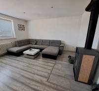 Wohnzimmer mit Ecksofa, Kaminofen und Tisch in einem Einfamilienhaus.