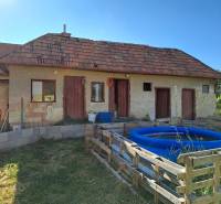 Ein Einfamilienhaus in Kmeťovo mit Anbau, aufblasbarem Pool und einfachem Holzzaun.