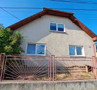 Ein Einfamilienhaus in Kmeťovo mit weißer Fassade und einem Metallzaun.