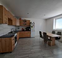 Küche in einem Einfamilienhaus mit Holzschränken, Esstisch und Geräten.