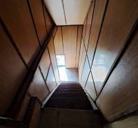 Eine Treppe mit Holzwänden, die zu einem schmalen Fenster in einem Einfamilienhaus führt.