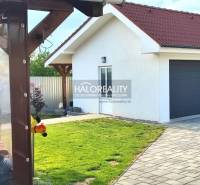 Außenbereich eines Einfamilienhauses in Kalinovo mit Rasen, Terrasse und Doppelgarage.