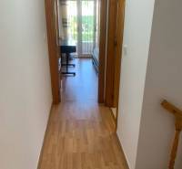 Der Flur des Einfamilienhauses führt in ein Zimmer mit einem Bett und einem Schreibtisch.