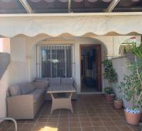 Ein Einfamilienhaus in Santiago de la Ribera mit Terrasse, Holzmöbeln und Blumentöpfen.