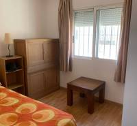 Ein Zimmer in einem Einfamilienhaus mit Holzmöbeln und einer Bettdecke.