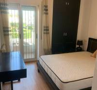 Schlafzimmer im Einfamilienhaus mit Bett, Schreibtisch und Zugang zum Balkon.