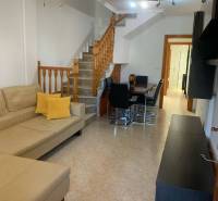Wohnzimmer eines Einfamilienhauses mit beigem Sofa, Esstisch und Holztreppe.