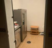 Waschküche in einem Einfamilienhaus mit Kühlschrank, Waschmaschine und kleinem Tisch auf gefliestem Boden.