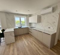 Helle Küche mit Marmorfliesen und Holzboden in einer Zweizimmerwohnung.