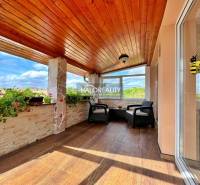 Eine verglaste Terrasse mit Holzdecke und Blumen in einem Einfamilienhaus.