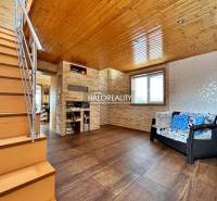 Innenraum eines Einfamilienhauses mit Holzdecke, Treppe und Sitzgarnitur.