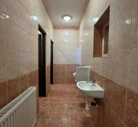 Badezimmer in Geschäftsräumen mit Waschbecken und Fliesen in Brauntönen.