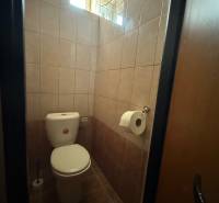 Eine Toilette mit gefliesten Wänden in Geschäftsräumen, mit einem Fenster für natürliches Licht.