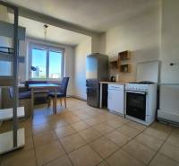 Küche in einer 2-Zimmer-Wohnung mit Esstisch, Geräten und großem Fenster.