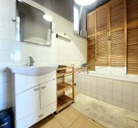 Badezimmer in einer 2-Zimmer-Wohnung mit Badewanne, Waschbecken und einem Holzschrank.