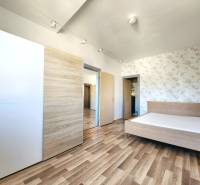 Schlafzimmer mit Holzboden, Bett und Einbauschrank in einer 2-Zimmer-Wohnung.