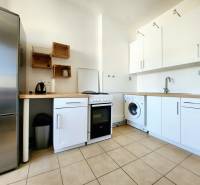 Küche in einer 2-Zimmer-Wohnung mit Geräten und minimalistischen Holzmöbeln.