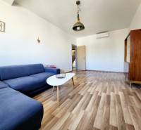 Wohnzimmer mit einem blauen Sofa, Holzboden und minimalistischen Möbeln in einer 2-Zimmer-Wohnung.