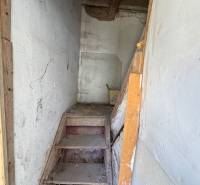Eine enge Holztreppe in Geschäftsräumen mit weißen Wänden und einer Balkendecke.